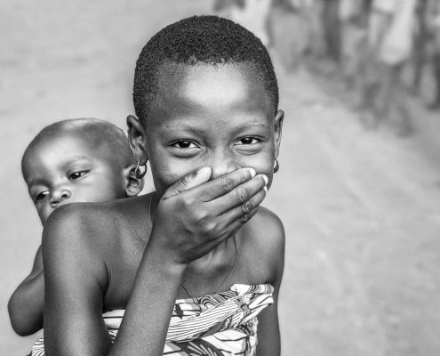 Girl in Benin, taking care of her little sibling, black and white